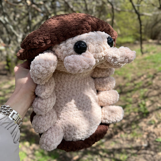 Plush crocheted  roly poly pill bug toy held in hand with natural background