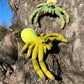 Crocheted crab spiders amigurumi sitting on a tree trunk outdoors
