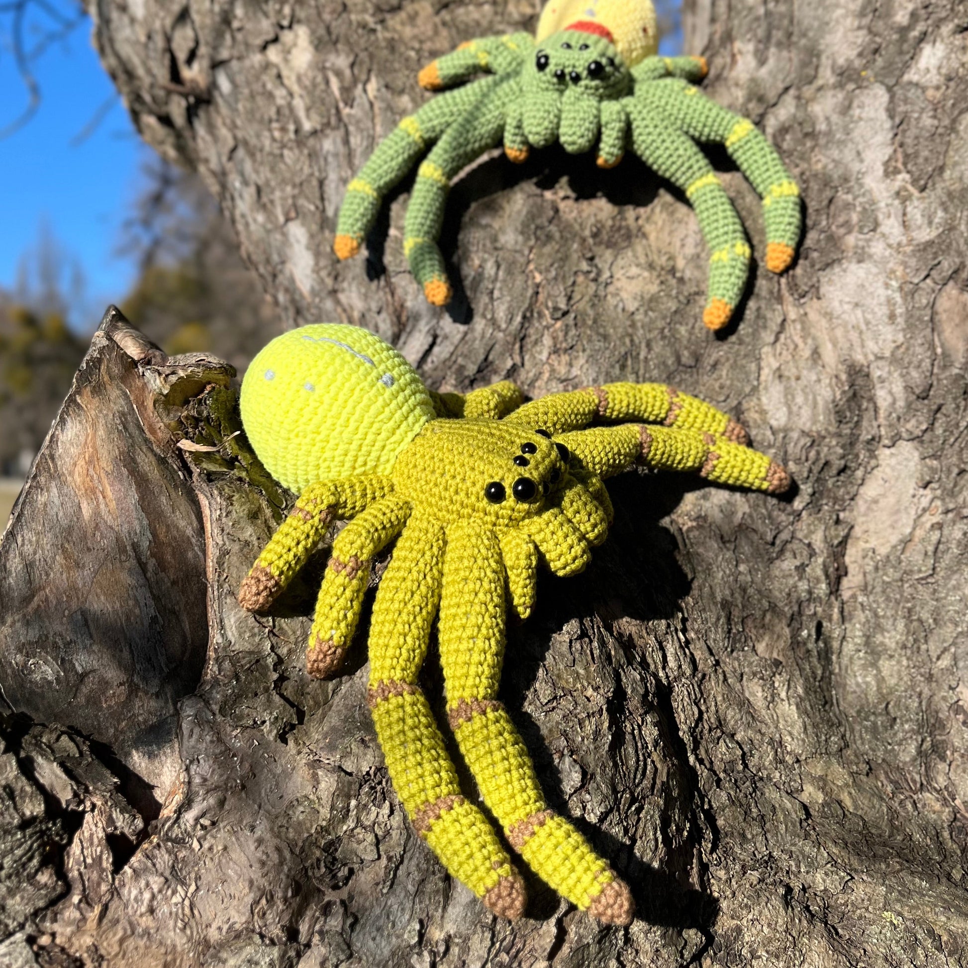 Crocheted crab spiders amigurumi sitting on a tree trunk outdoors